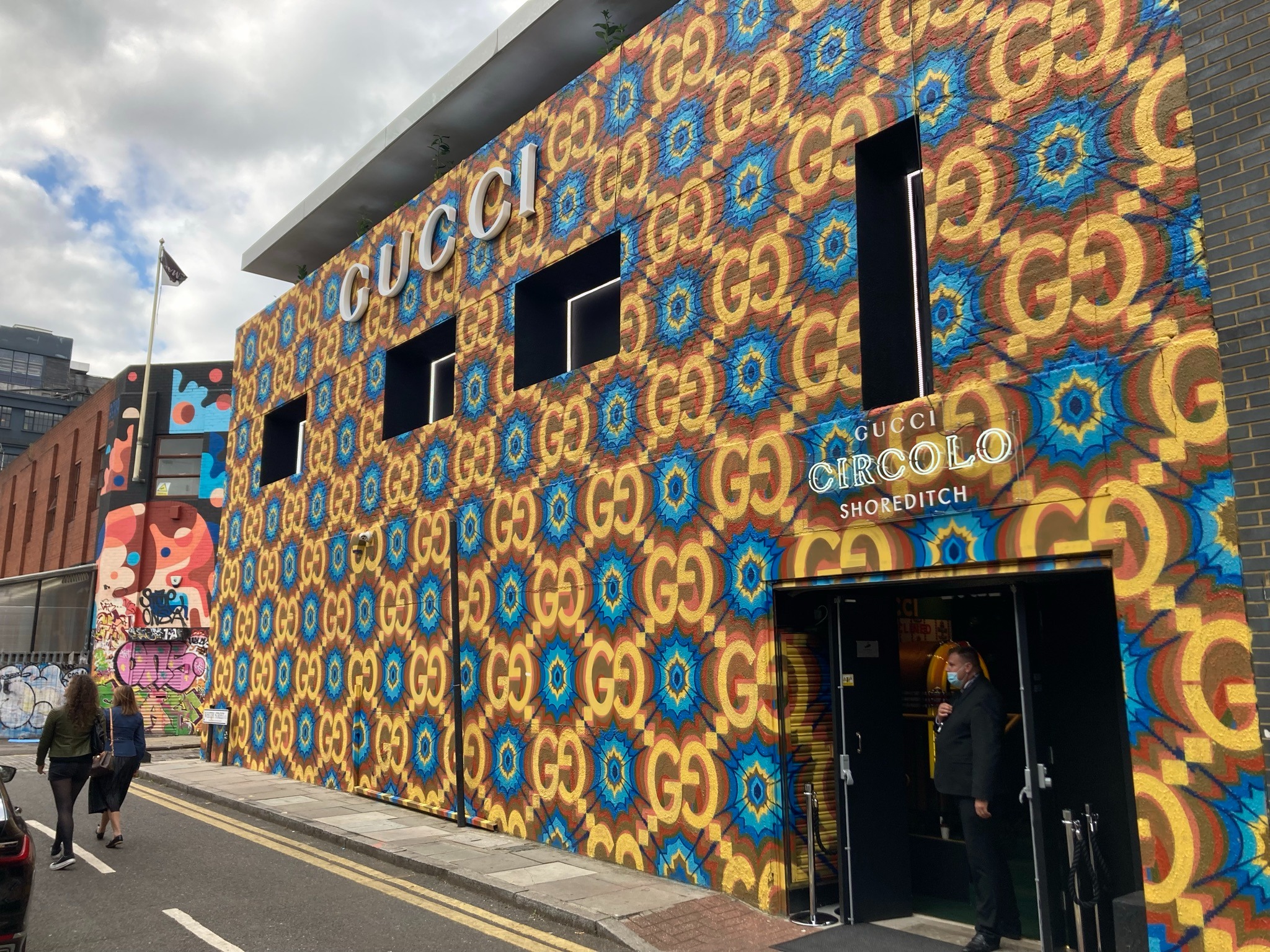 Façade du Gucci Circolo Shoreditch à Londres avec enseigne GUCCI, motifs GG multicolores et signalétique au-dessus de l’entrée.